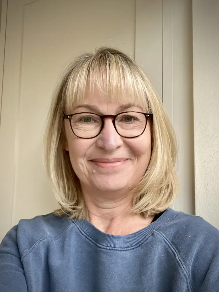 Helen White, Peaches PPV lead, white female, blonde shoulder length hair, wearing glasses and blue jumper