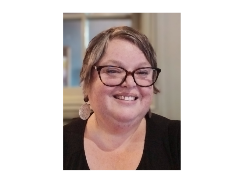Fay, Peaches supporter, white female with short brown hair, wearing glasses, disc earrings and black top