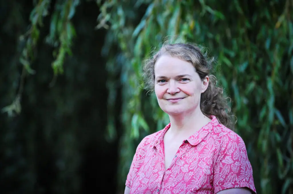 Image of Professor Emma Crosbie, white female, long curly hair wearing pink patterned shirt